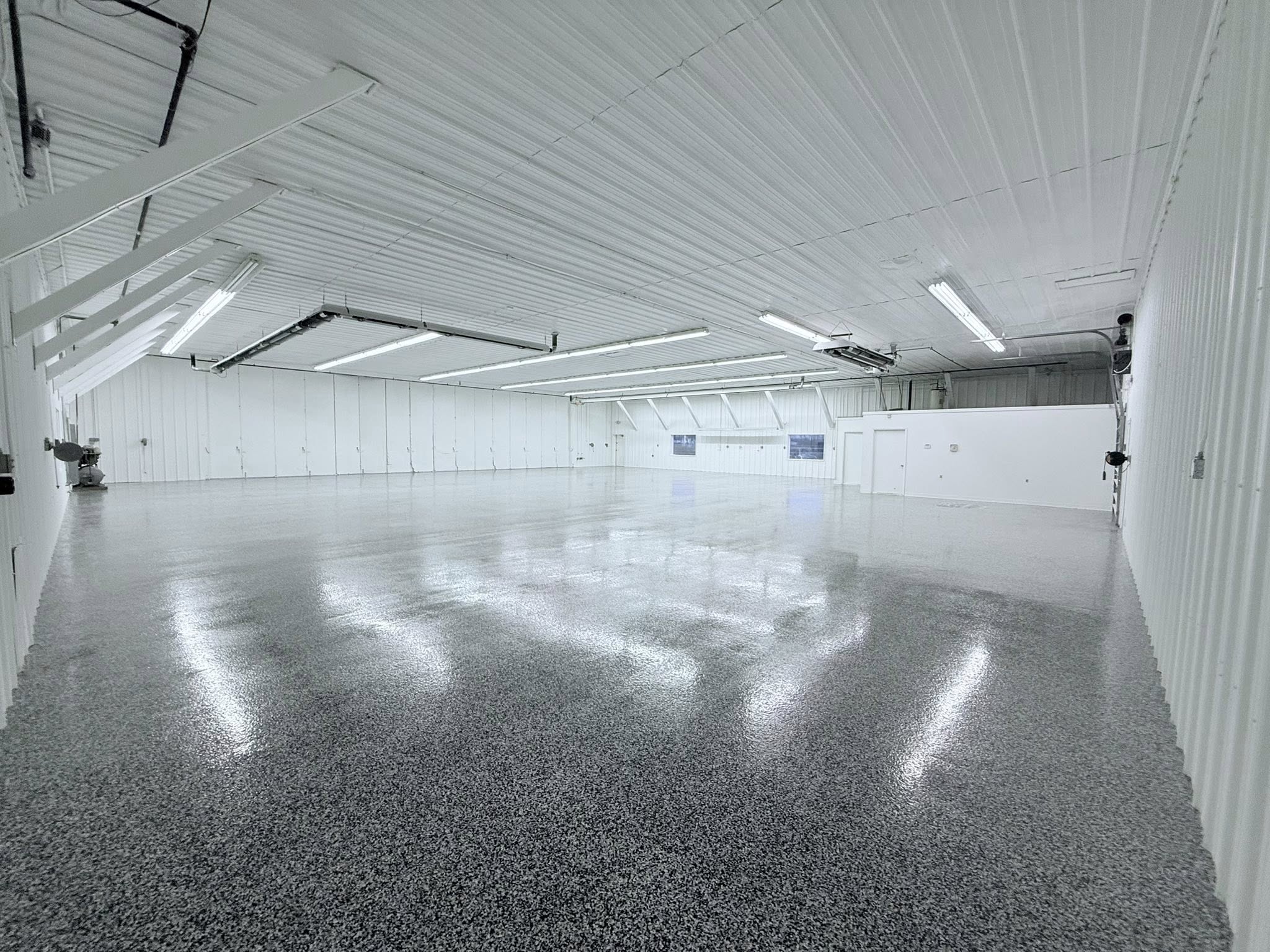 Expansive commercial shop interior with a glossy gray flake-epoxy floor reflecting the overhead lights
